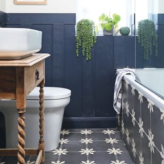 Bathroom with grey wall panelling and patterned floor and bath tiles