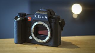 Leica SL3 camera on a wooden surface against a blue background