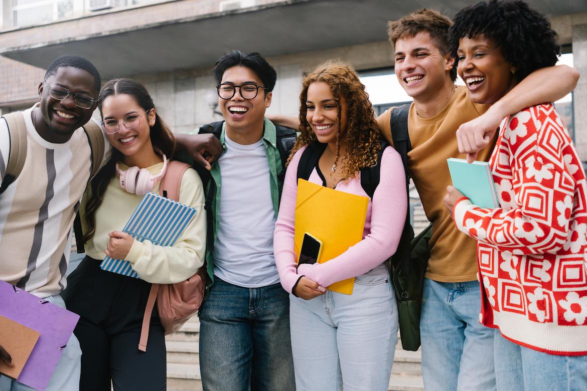 A group of 6 students holding books and smiling for the camera