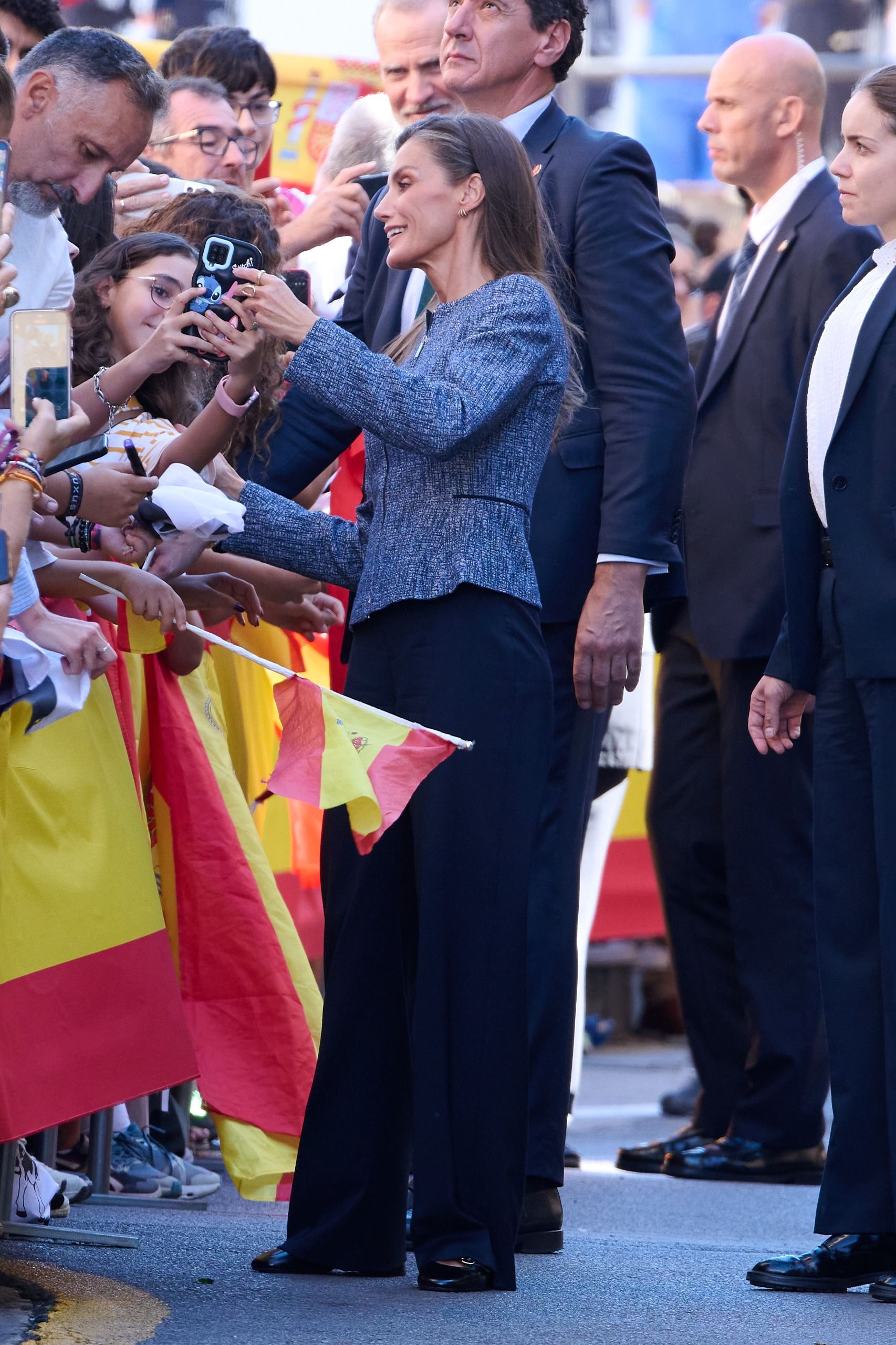 Queen Letizia taking photos with fans hanging over a barrier