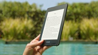 Am See lesen? Kein Problem. Jemand hält einen Amazon Kindle in der Hand