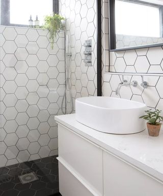 A white tiled bathroom with frameless shower
