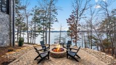 Chairs circle a firepit at a home on a lake