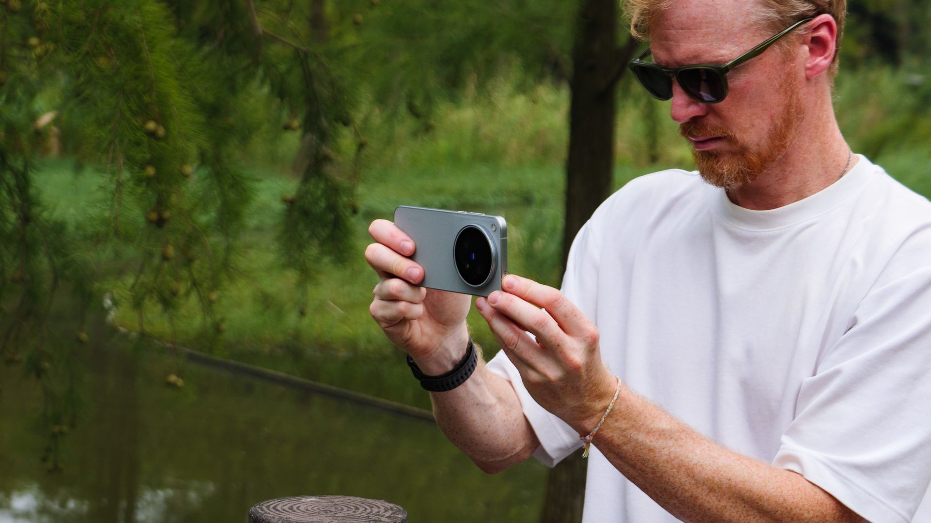 Tim Coleman, TechRadar's Cameras Editor, holding the Vivo X500 Pro Max phone while stood on a wooden walkway in a birdlife reserve in Shanghai, China