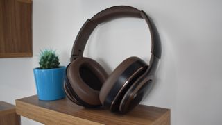 Hero image for cheap wireless headphones showing the Cleer Enduro ANC propped on a wooden shelf