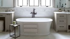 White bathroom with beige vanity units and white freestanding bath