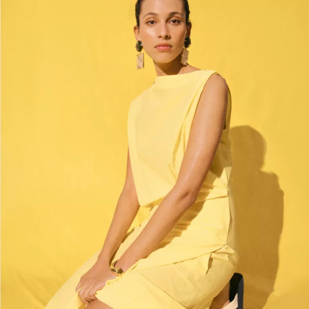 Woman wearing light yellow Selfridges dress with yellow background
