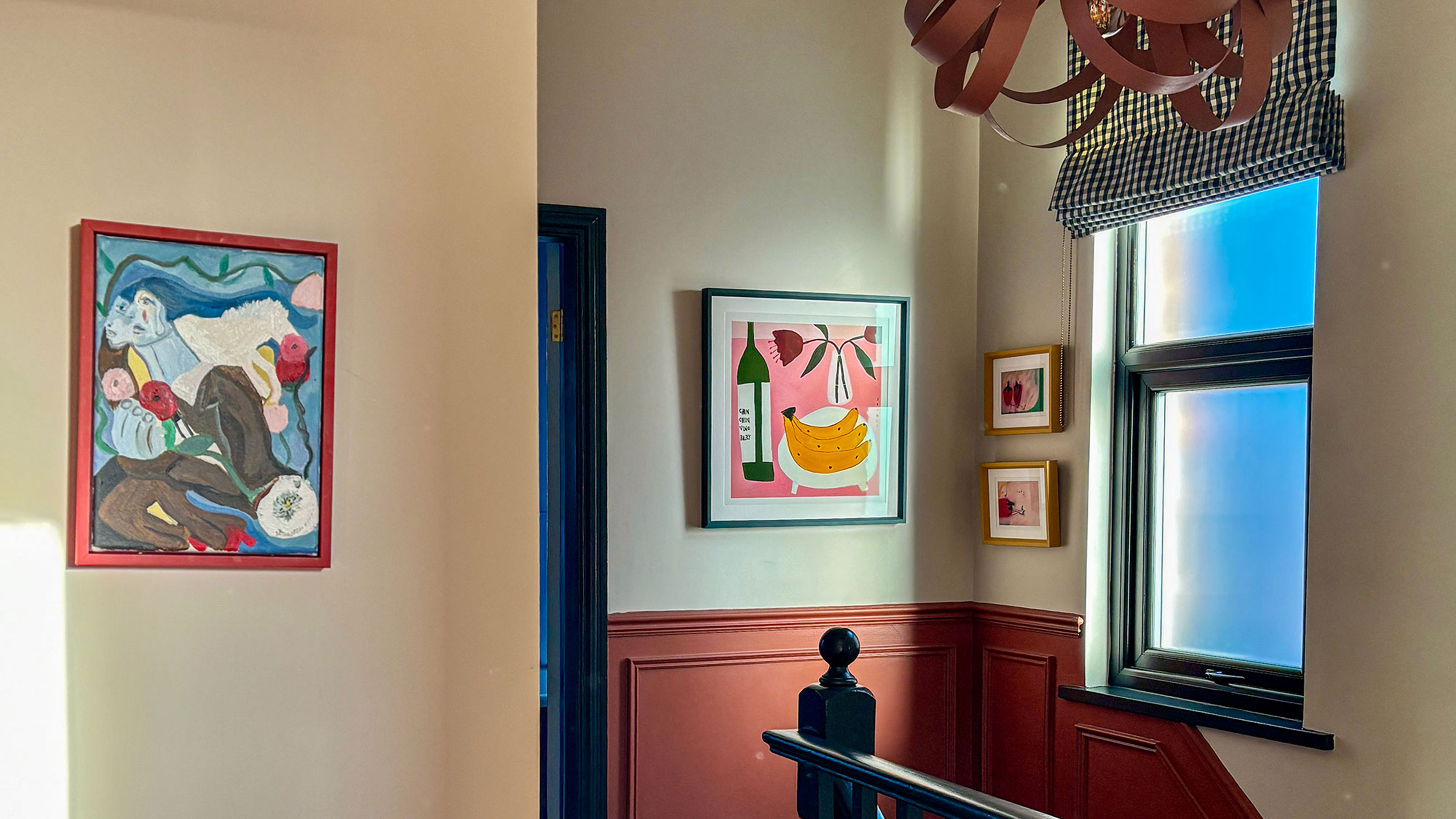 Landing area with painted panelling, statement pendant light and paintings on walls