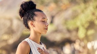 A woman breathing with her eyes closed and a hand on her chest