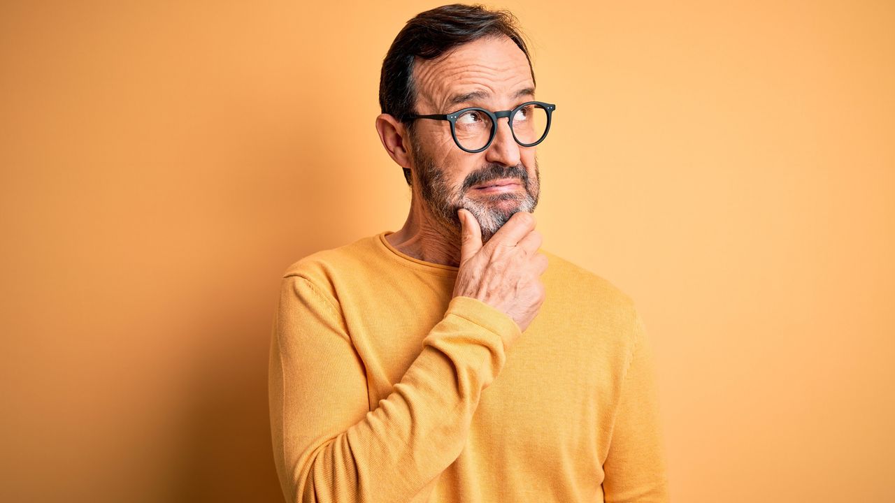 An older man has a questioning look on his face as he looks into the distance.