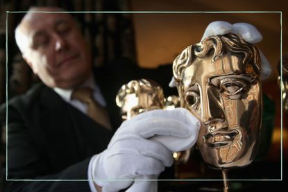a close up of a man polishing the BAFTA award - a gold mask
