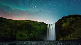 northern lights over waterfall in iceland