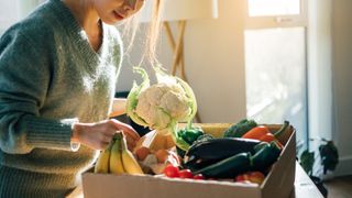 woman unboxing vegetables delivered to her home