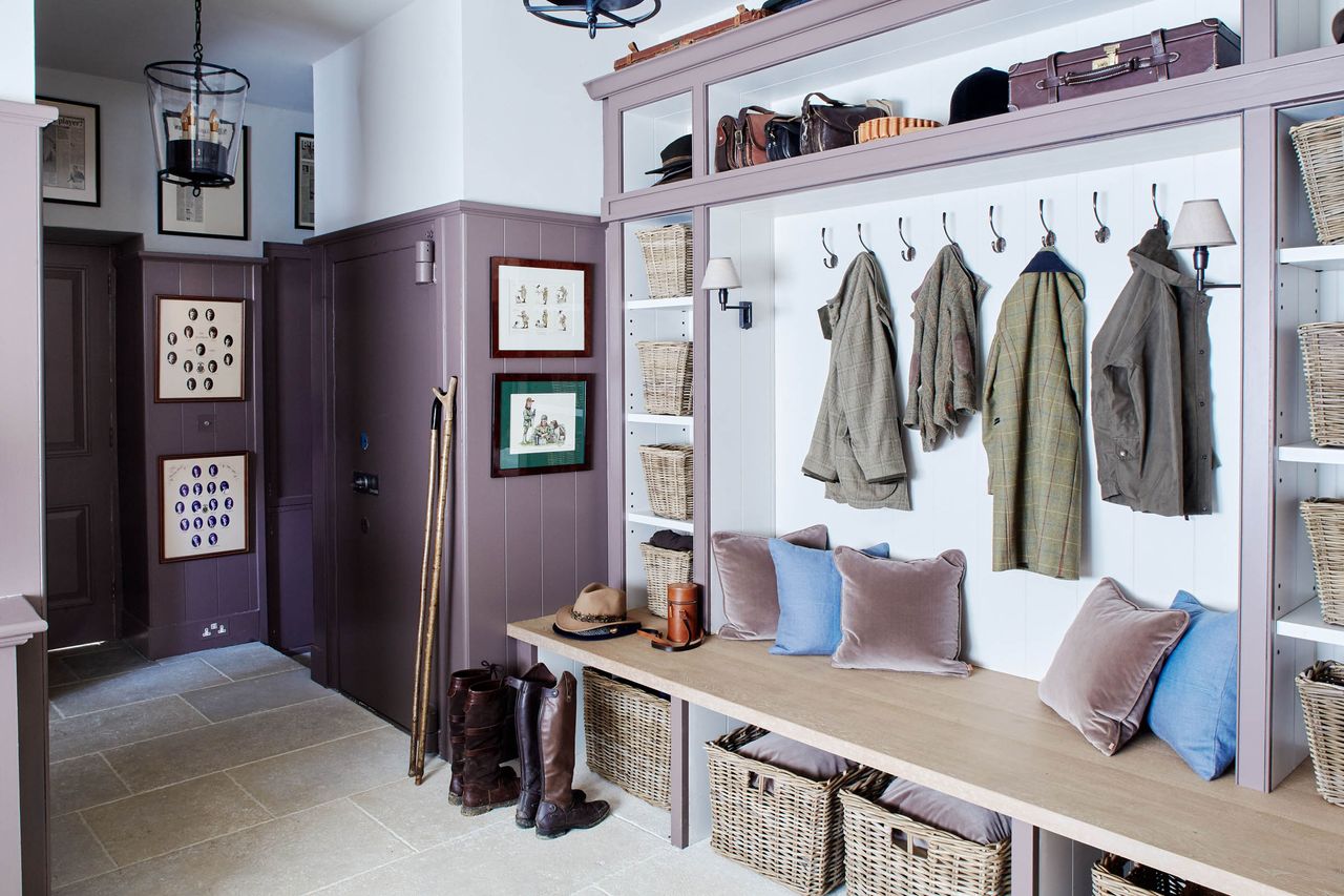 A large mudroom with purple wall paneling and a wooden bench with velvet cushions