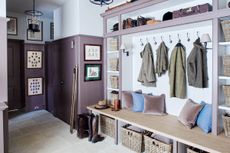 A large mudroom with purple wall paneling and a wooden bench with velvet cushions