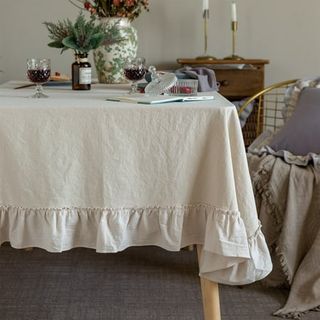 A frilly hemmed cream tablecloth on a rectangular table