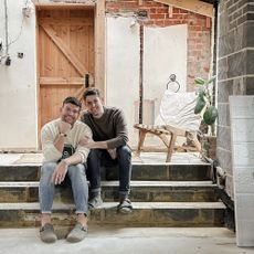 David and Andrew Harrison-Colley pictured at home sitting on a step with a wooden door behind