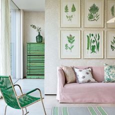 Neutral room with light floral wallpaper, pink sofa and a green chair