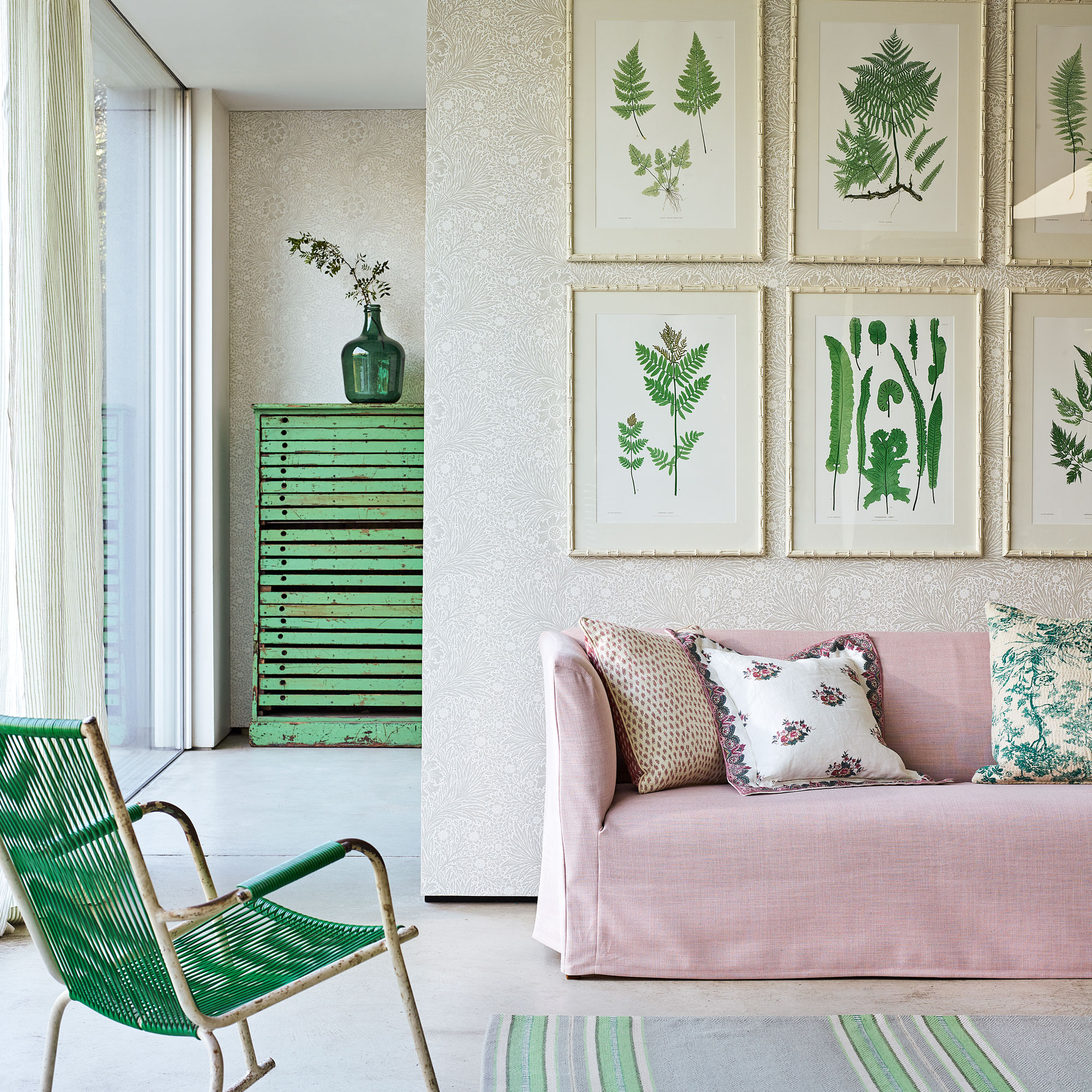 Neutral room with light floral wallpaper, pink sofa and a green chair