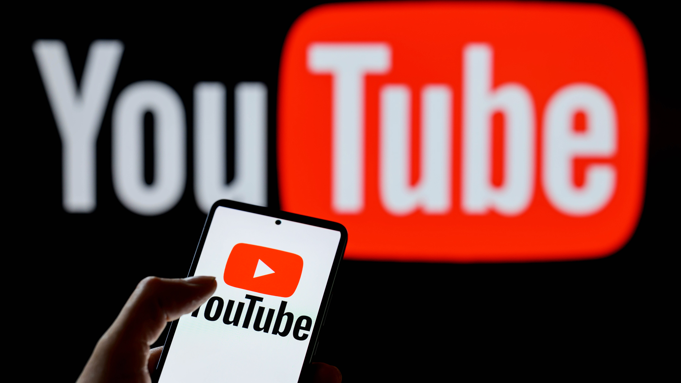 The YouTube play logo is being displayed on a smartphone, with YouTube in the background, in this photo illustration in Brussels, Belgium, on July 24, 2024. (Photo Illustration by Jonathan Raa/NurPhoto via Getty Images)