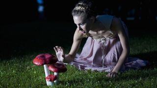 Woman in a white dress reaching out to touch a mushroom at night