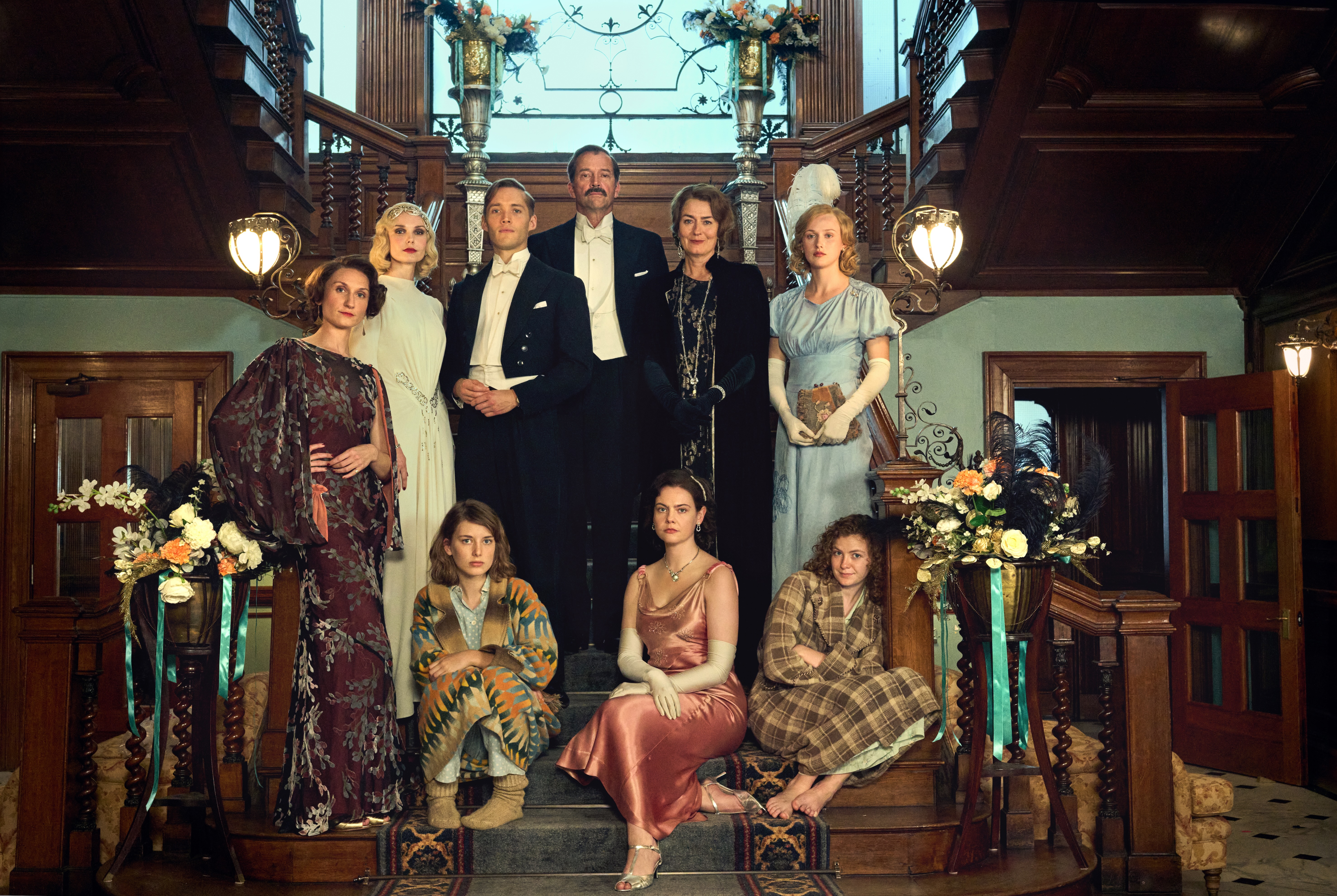 Actors and actresses in 1930s period dress, posing on a grand staircase