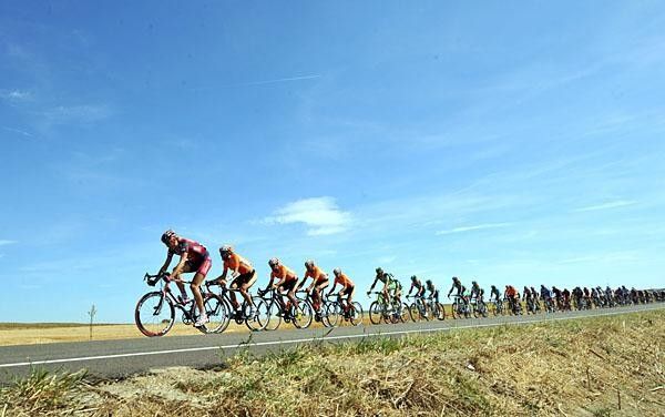 The peloton begins the chase, under a clear sky.