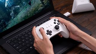 A player using the 8BitDo Ultimate Controller with a laptop