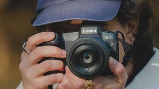 Man wearing a cap and holding a Canon EOS camera
