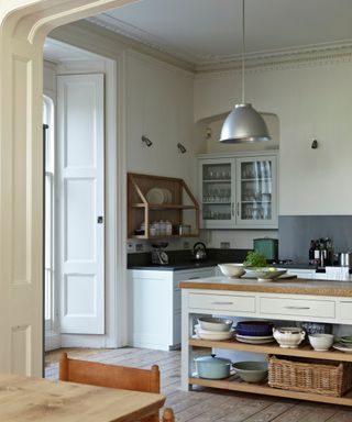 kitchen with white walls, butcher's block island unit, wooden floors, silver pendant and large window