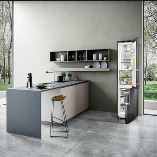 grey fridge/freezer on a grey kitchen floor, with a kitchen island