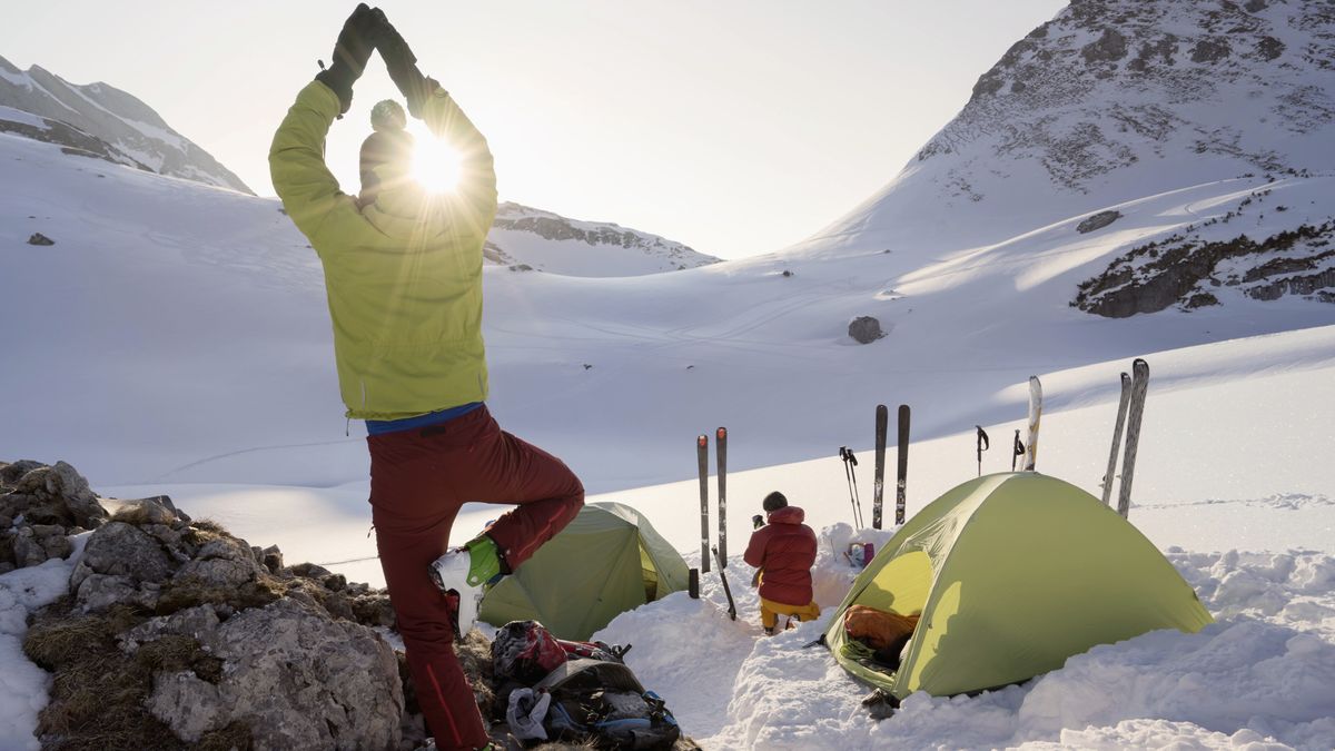 A skier doing tree pose in the mountains