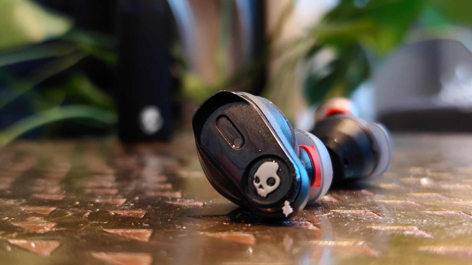 The Skullcandy Method 540 earbud, with another bud and the case in the background.