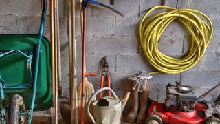 A garden hose stored alongside other tools inside a shed