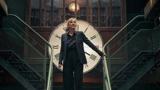 Before We Die season 2: Hannah Laing (Lesley Sharp) stands on a staircase in front of a large clock. The staircase extends both to the left and to the right behind her, leading to an upper floor.