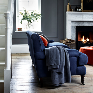 Grey armchair with a log burning fireplace