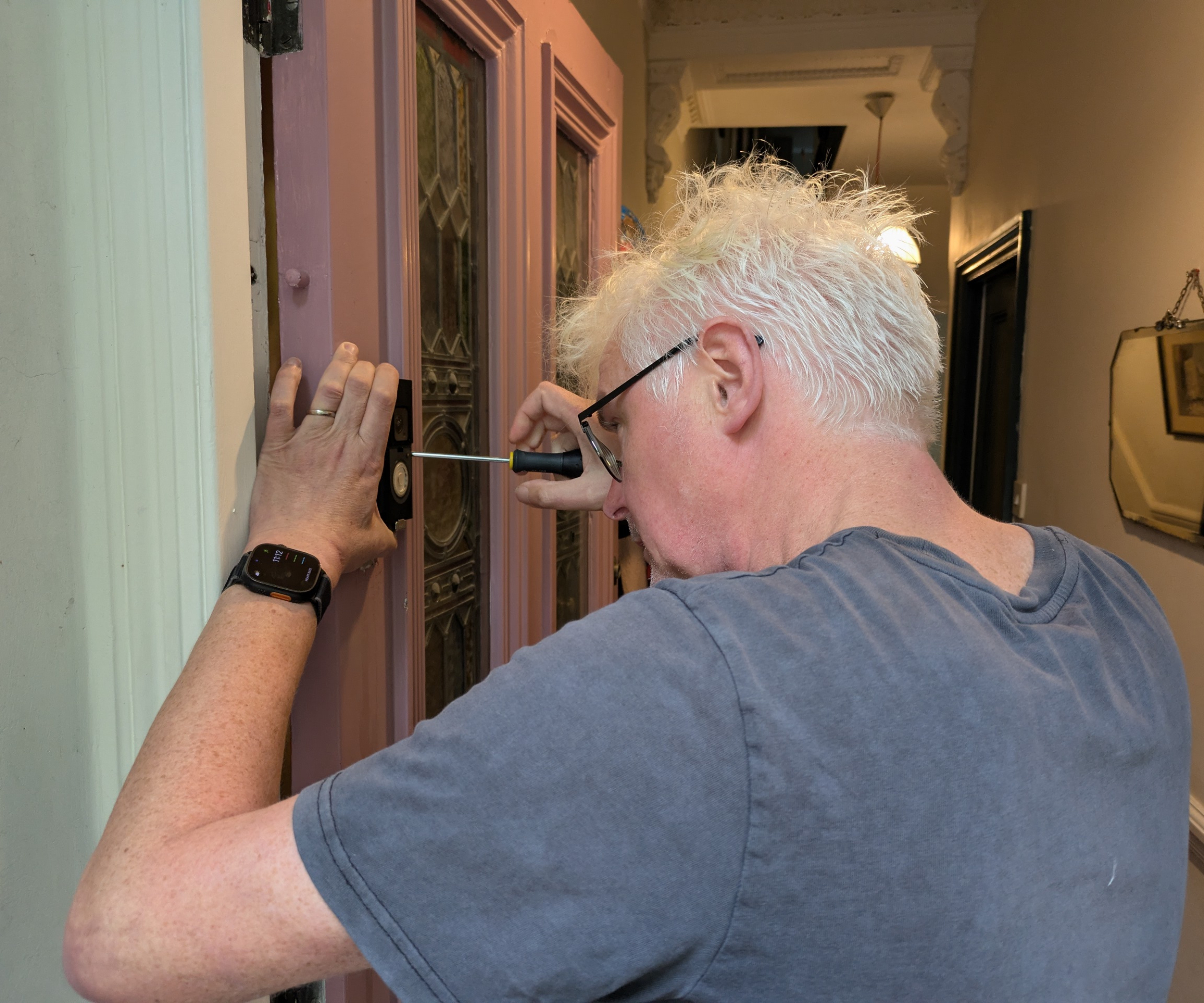 man fitting video doorbell to front door frame
