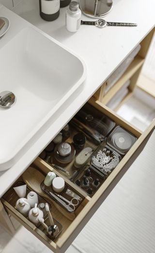 A neatly organized bathroom drawer with compartments for toothbrushes, skin care, nail clippers and more