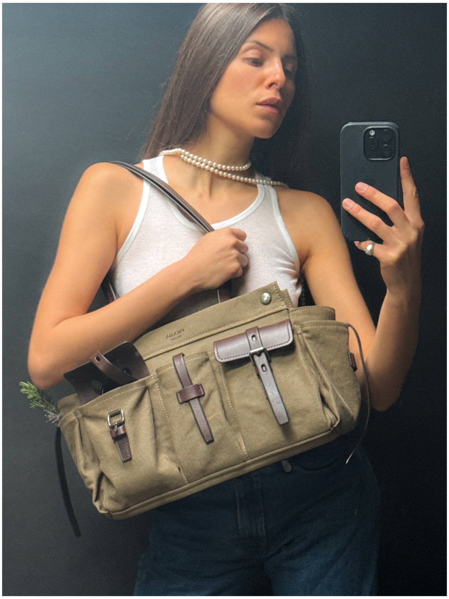 @majawyh in a white tank top and pearl necklace while carrying a green canvas Prada Route bag.