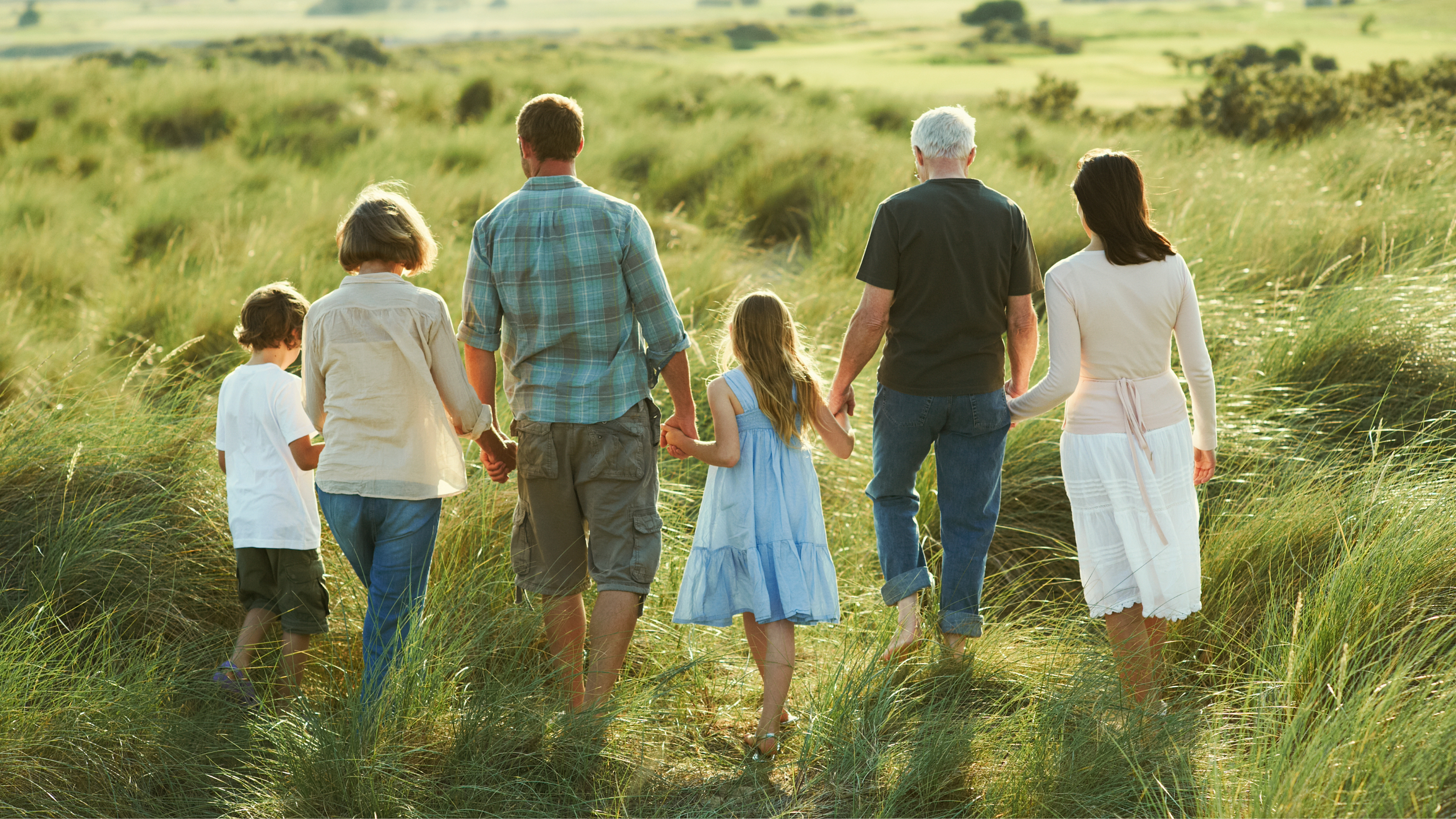 Multigenerational family walking on a field holding hands