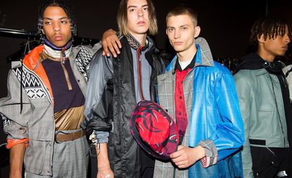 Four male models facing the camera at a fashion week wearing bright clothes