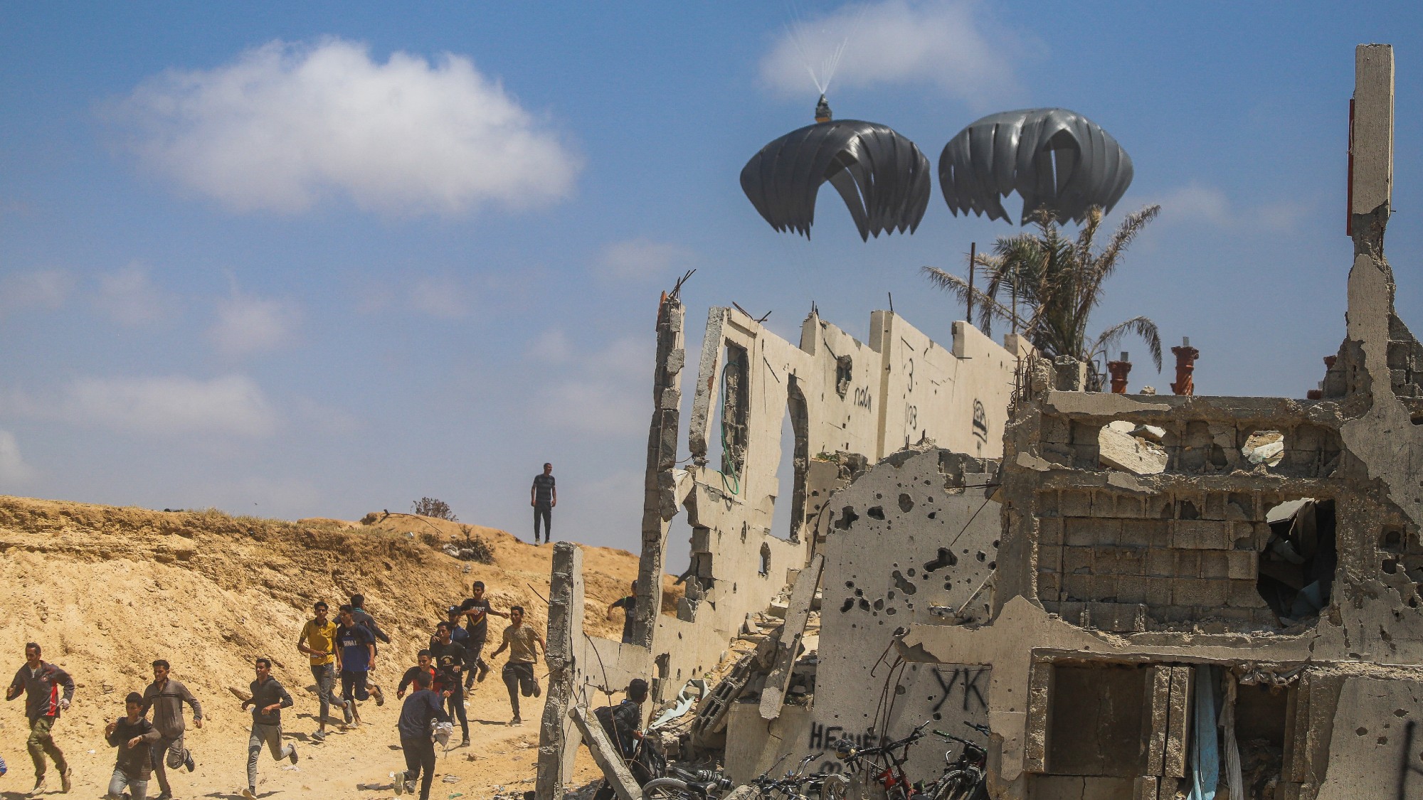 Palestinians race to pick up airdropped aid packages in Gaza on April 30, 2024.