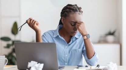 How to manage stress at work: A woman at her desk looking stressed
