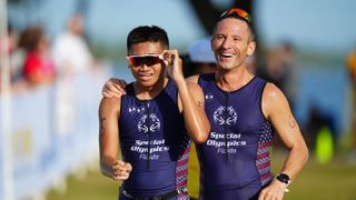 Two triathlon athletes, one of whom is wearing a visor, run together in Orlando Florida at the 2022 Special Olympics USA Games. Decorative: The shot has been taken on a telephoto lens, in a very shallow depth of field.