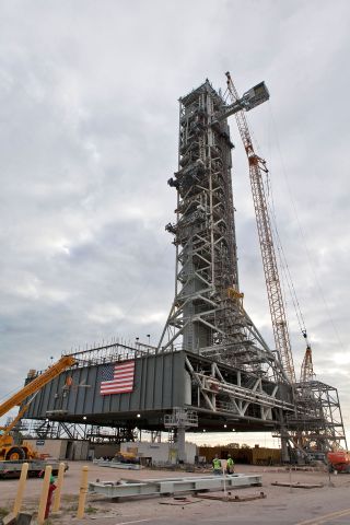 At NASA's Kennedy Space Center in Florida, a crane positions the Orion crew access arm so it can be attached to the Space Launch System mobile launcher.