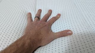 A hand touching the surface of the Eva Comfort Classic mattress