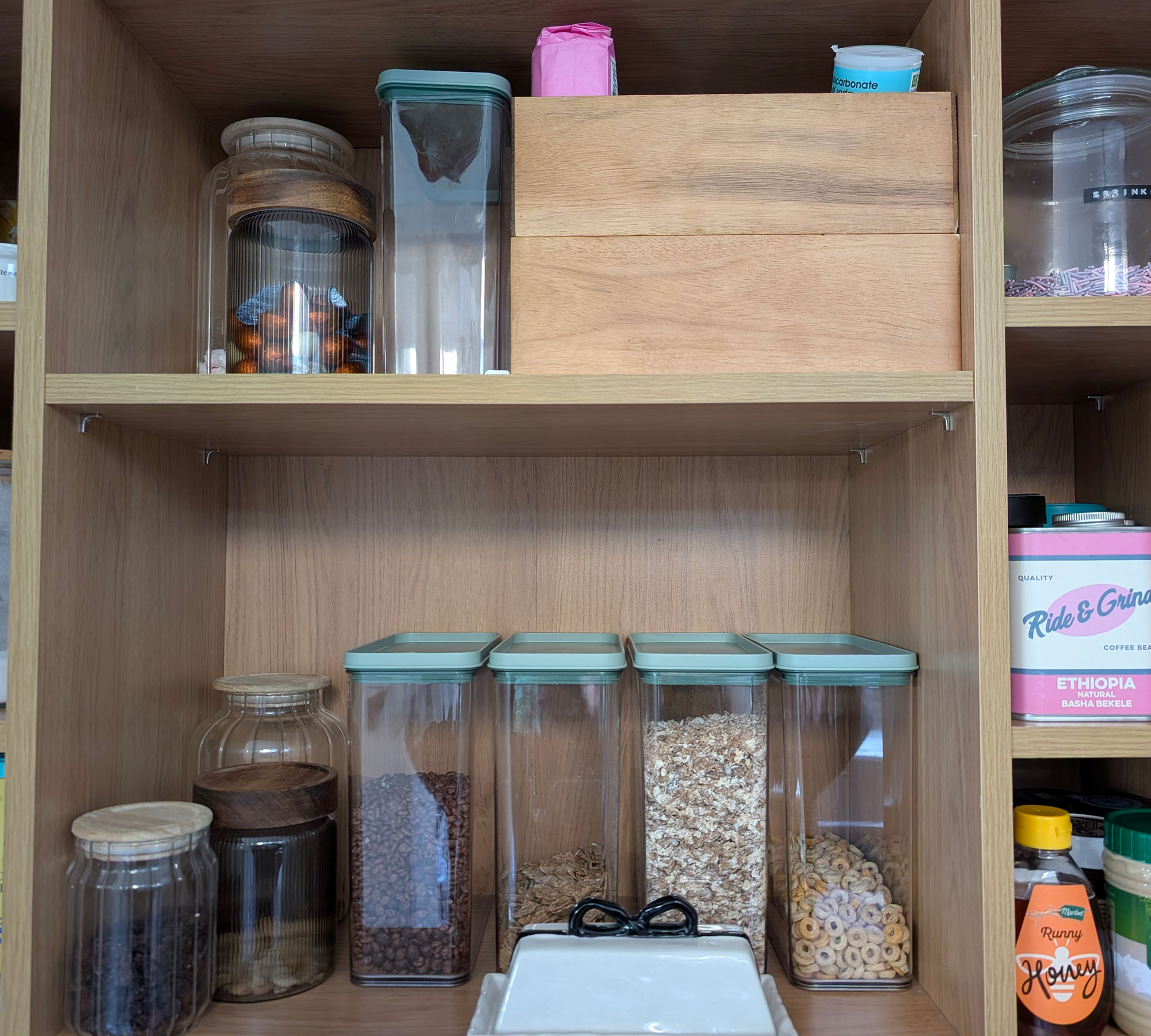 Open cupboard showing food organised into plastic and glass jars