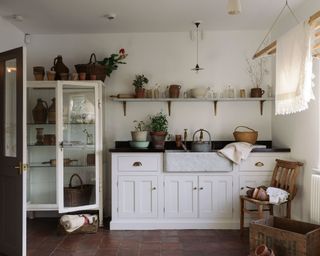 An eclectic utility room idea with open shelving laden with vases, pots and baskets full of fresh flowers.