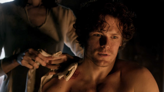 sam heughan as jamie while claire tends his wounds in outlander season 1