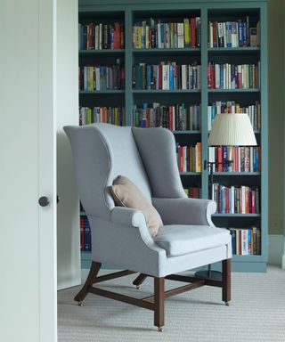 Tall winged back armchair in front of inbuilt shelving living room by Fran Hickman